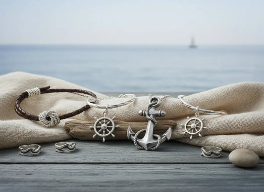Bijoux marins représentant gouvernails, cordages et ancres posés sur une table en bois, vue sur la mer en arrière-plan.