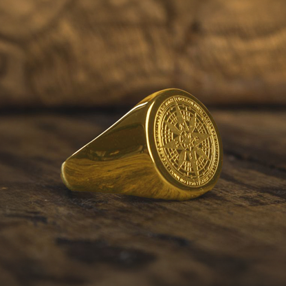 Bague boussole pirate dorée en acier inoxydable posée sur un bois vieilli, bijou corsaire au style vintage évoquant les trésors et la navigation maritime.