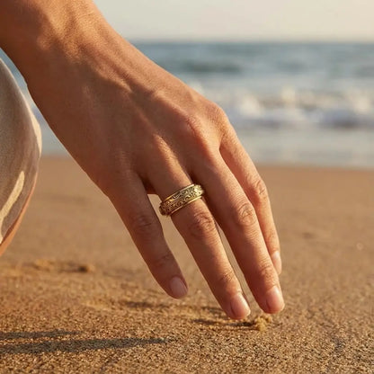 Bague astrale dorée portée par une femme sur la plage, bijou symbolique et élégant.