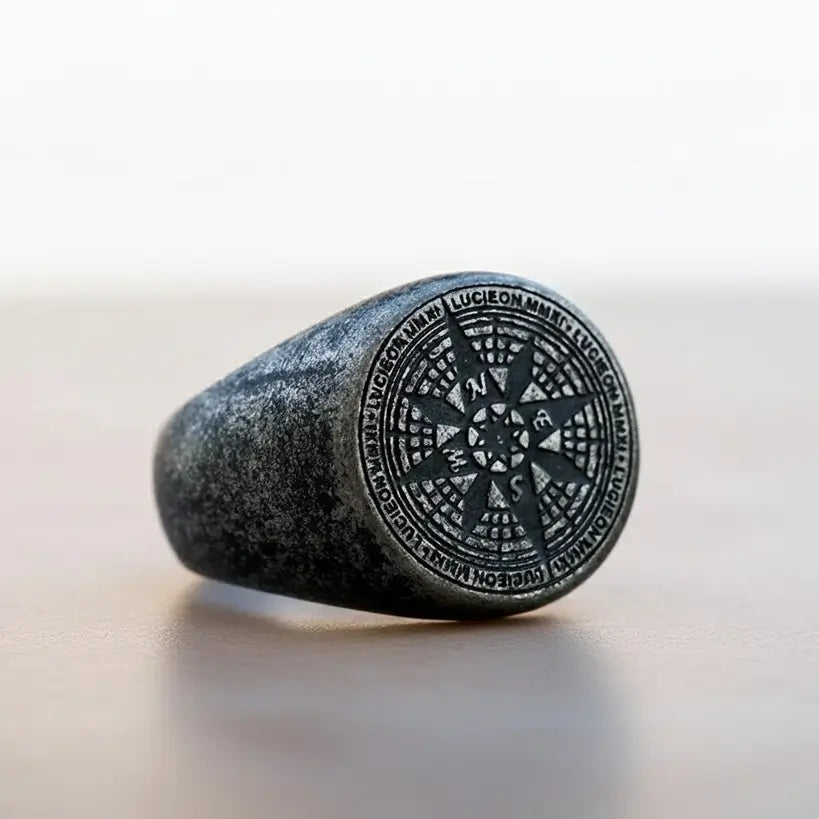Bague boussole noire vue de près, mettant en valeur les détails de la gravure.