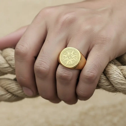 Bague boussole dorée portée sur une main tenant une corde, ambiance maritime authentique.