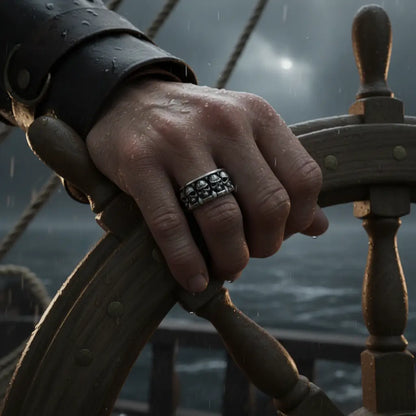 Homme tenant la barre d’un navire, portant la Bague Empire des Crânes, lumière dramatique.