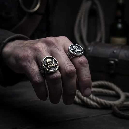 Main d’un pirate portant les deux bagues argent et or du flibustier maudit 316L, ambiance dramatique sombre.