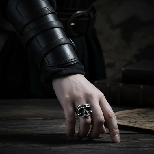 Bague du Fragment Crânien portée à la main posée sur une table en bois, ambiance ténébreuse.