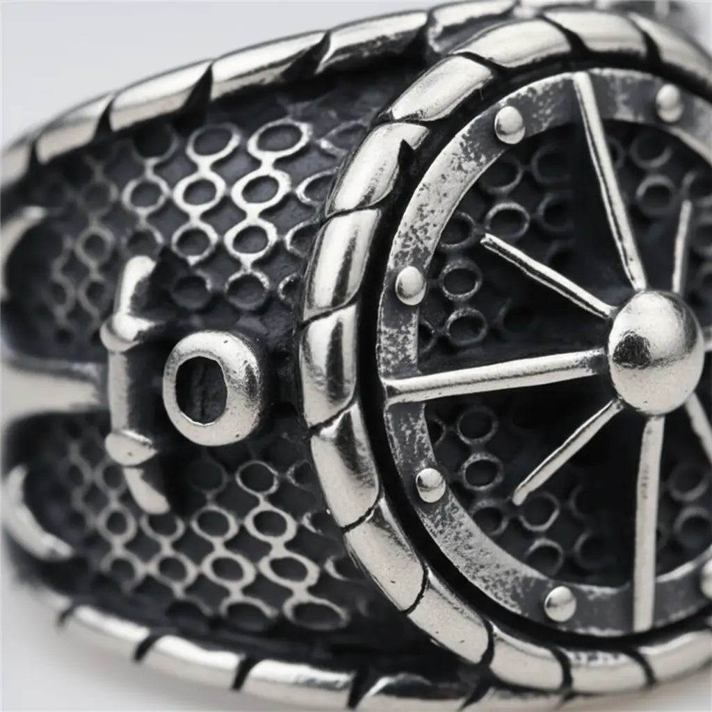 Gros plan sur la gravure de la bague gouvernail du capitaine 316L, texture acier brossé et relief.