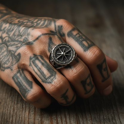Bague gouvernail pirate portée sur une main tatouée, style capitaine et aventurier.