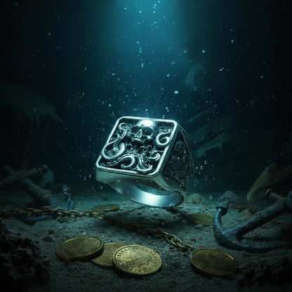 Bague Kraken 316L entourée de pièces d’or sur un sol marin sombre, atmosphère mystérieuse.