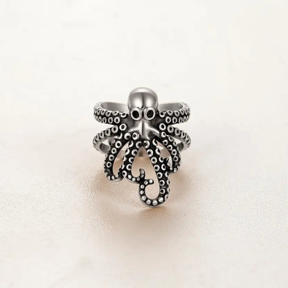 Bague pieuvre enroulée en argent sur fond blanc minimaliste.
