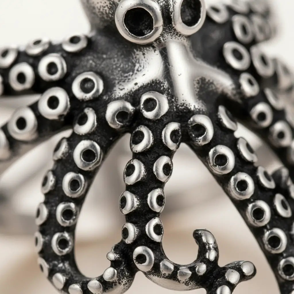 Détail macro du bijou pieuvre enroulée, tentacules et texture argentée.