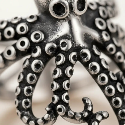 Détail macro du bijou pieuvre enroulée, tentacules et texture argentée.