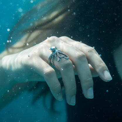 Bague pieuvre enroulée portée par une femme sous l’eau, ambiance abyssale.