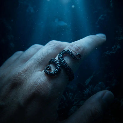 Bague tentaculaire portée à la main dans une ambiance marine nocturne.