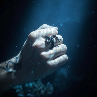 Bague tentaculaire portée à la main dans une ambiance océanique sombre.