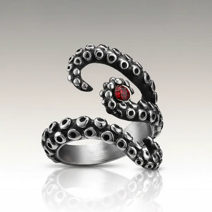 Bague des tentacules argentées avec pierre rouge centrale sur fond clair.