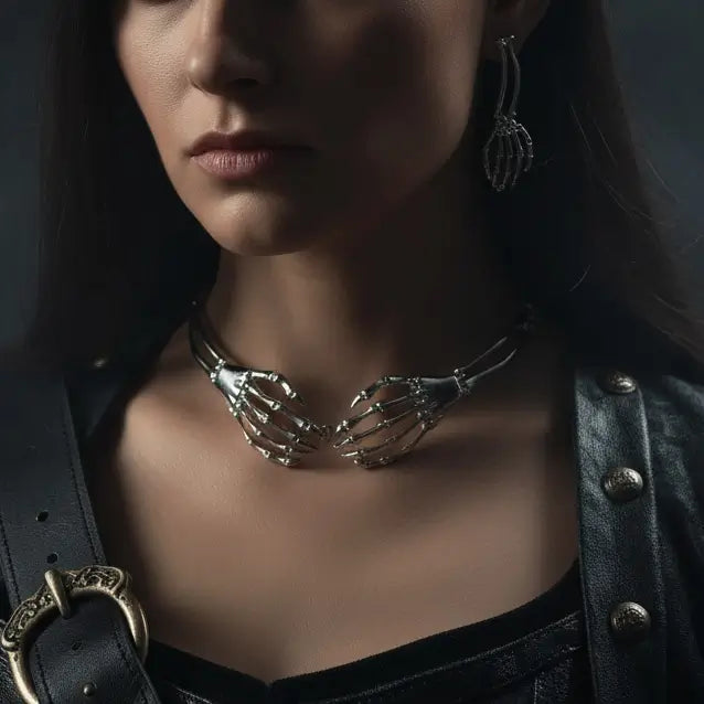 Gros plan sur un modèle portant le collier et les boucles d’oreilles gothiques en forme de mains squelettes argentées.