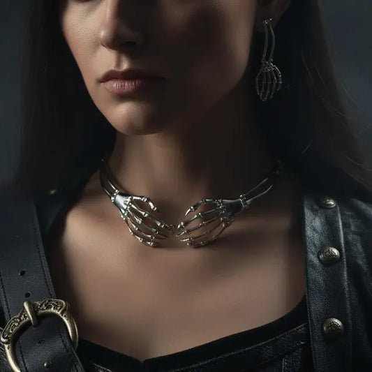 Gros plan sur un modèle portant le collier et les boucles d’oreilles gothiques en forme de mains squelettes argentées.