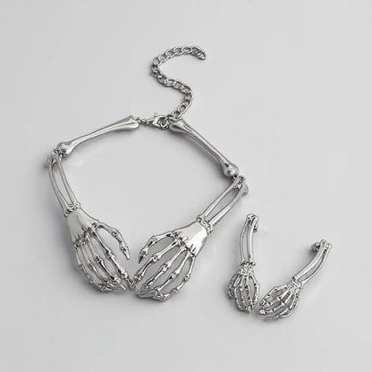 Set de bijoux gothiques argentés composé d’un collier squelette et de boucles d’oreilles assorties.