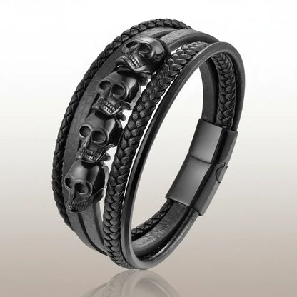 Bracelet du Repaire des Ombres avec crânes noirs et cuir tressé sur fond blanc.