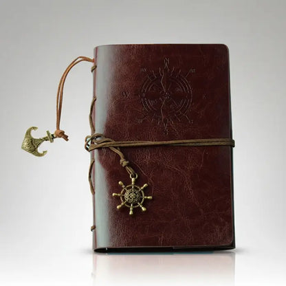Carnet pirate en cuir marron avec spirale rigide et boussole embossée, aspect vieilli et élégant.