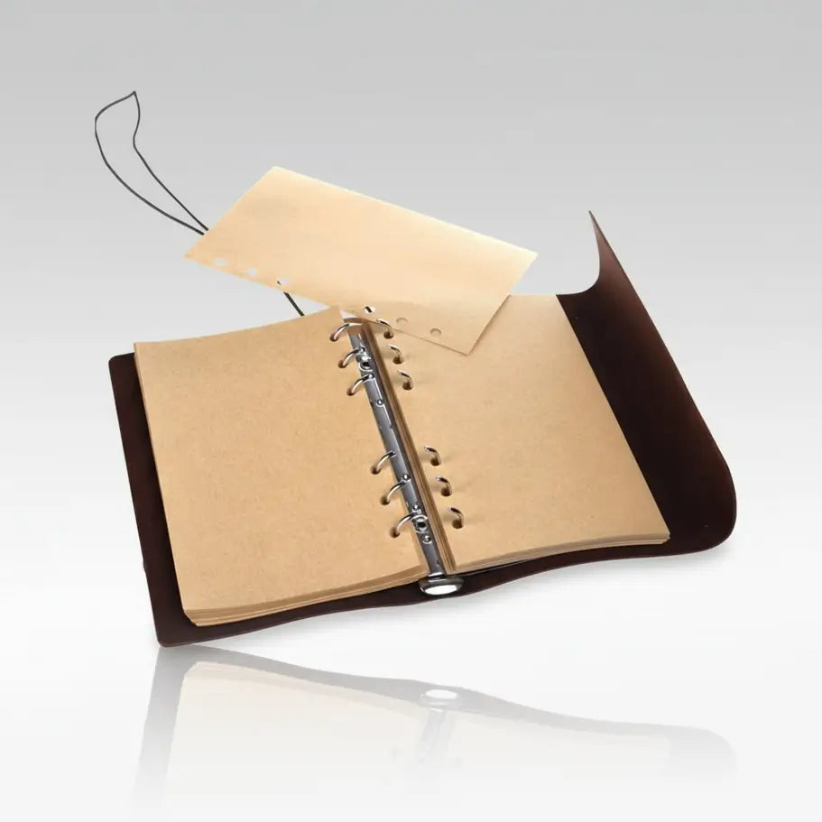 Carnet pirate en cuir ouvert, pages intérieures visibles avec spirale rigide et papier beige.