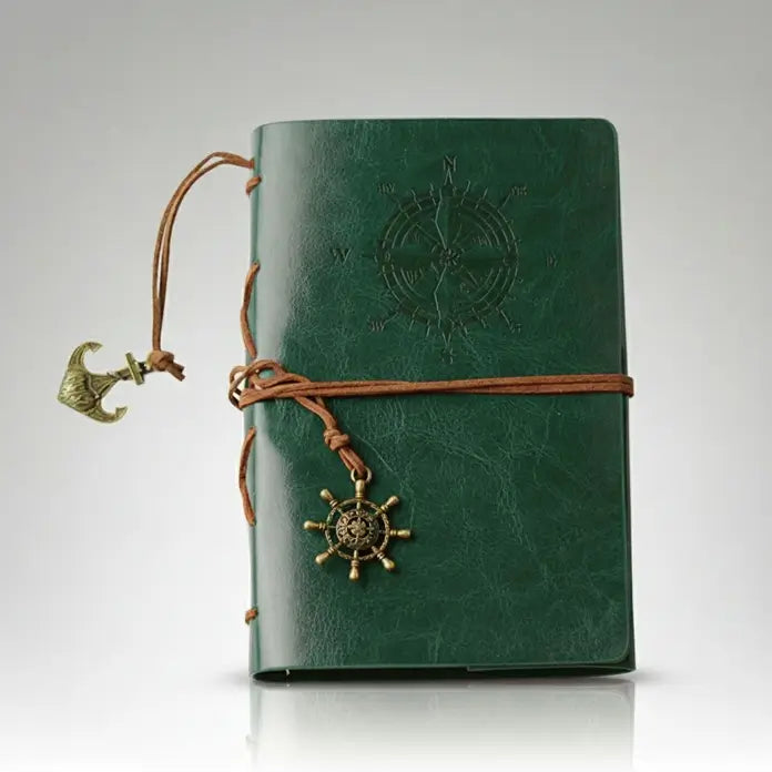 Carnet pirate en cuir vert orné d’une boussole gravée et d’un cordon de fermeture, style marin rétro.