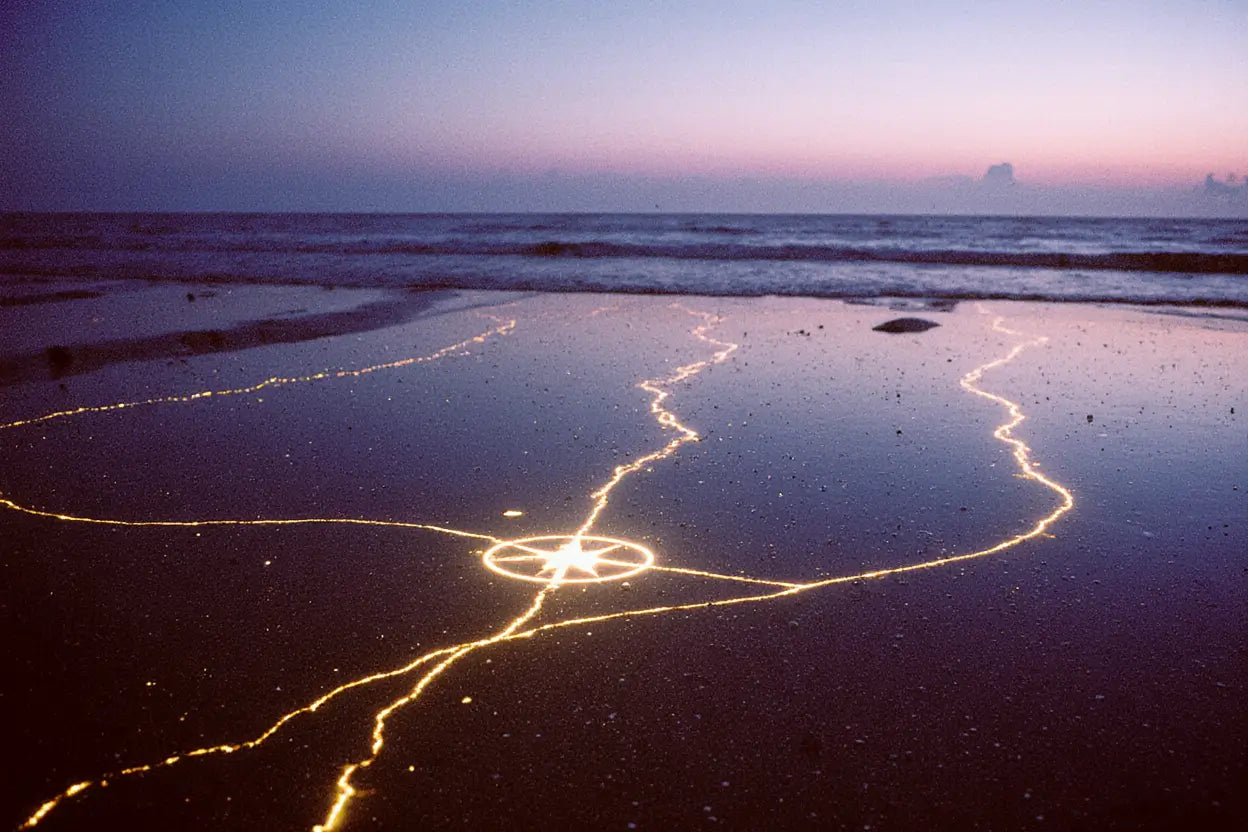 Chemins invisibles sur une plage du DESTIN avec trois lignes de feu émergeantes du sable.