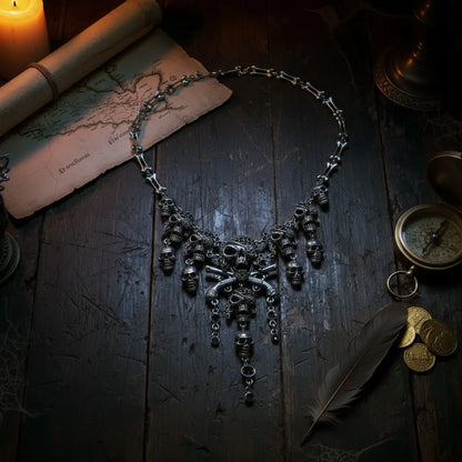 Collier Crâne Maudit argenté sur table en bois avec carte ancienne et chandelle, bijou pirate mystique.