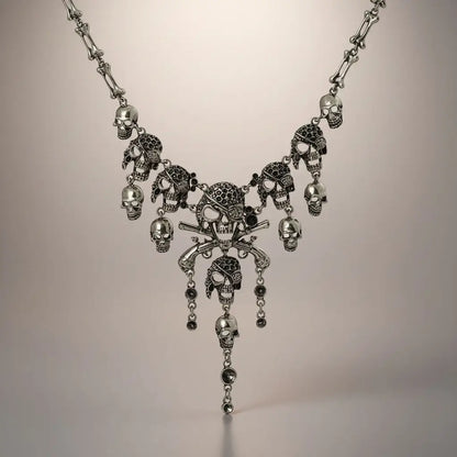 Collier Crâne Maudit argent sur fond neutre, bijou pirate de la gamme Ténèbres, orné de crânes et pendentifs croisés.