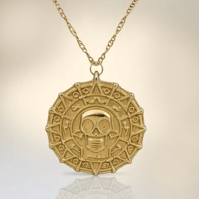 Photo produit du médaillon pirate des Caraïbes doré sur fond blanc teinte chaude, bijou inspiré des trésors enfouis.