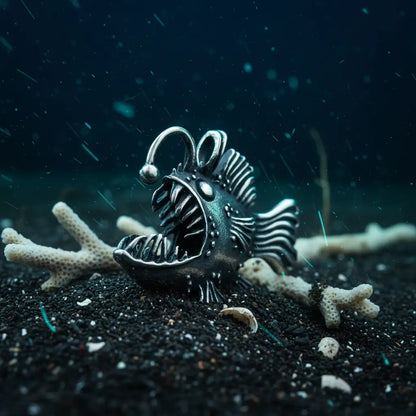Collier Poisson Squelette Lanterne argenté posé sur le sable marin avec coquillages et coraux.