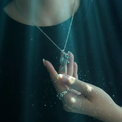 Collier Poisson Squelette Piranha tenu dans la main d’une femme, effet d’immersion aquatique.