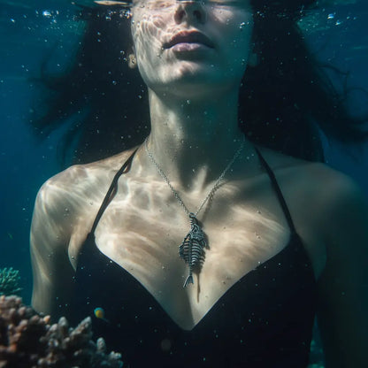 Collier Poisson Squelette Thon porté par une femme sous l’eau, ambiance aquatique et mystérieuse.