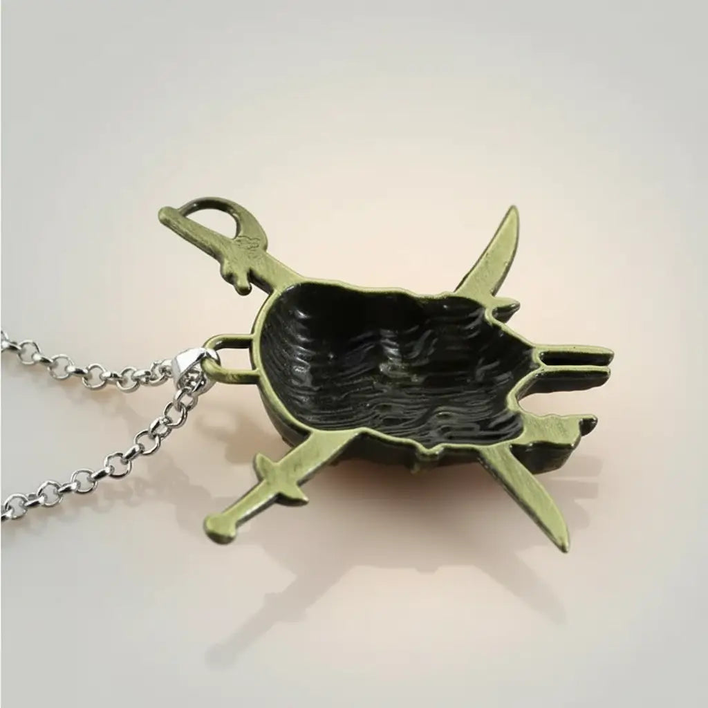 Gros plan sur le face arrière creuse du pendentif sabres flibustier bronze.