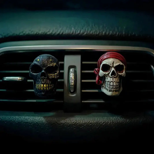 Deux désodorisants en forme de crâne installés sur la grille d’aération d’une voiture, ambiance sombre.