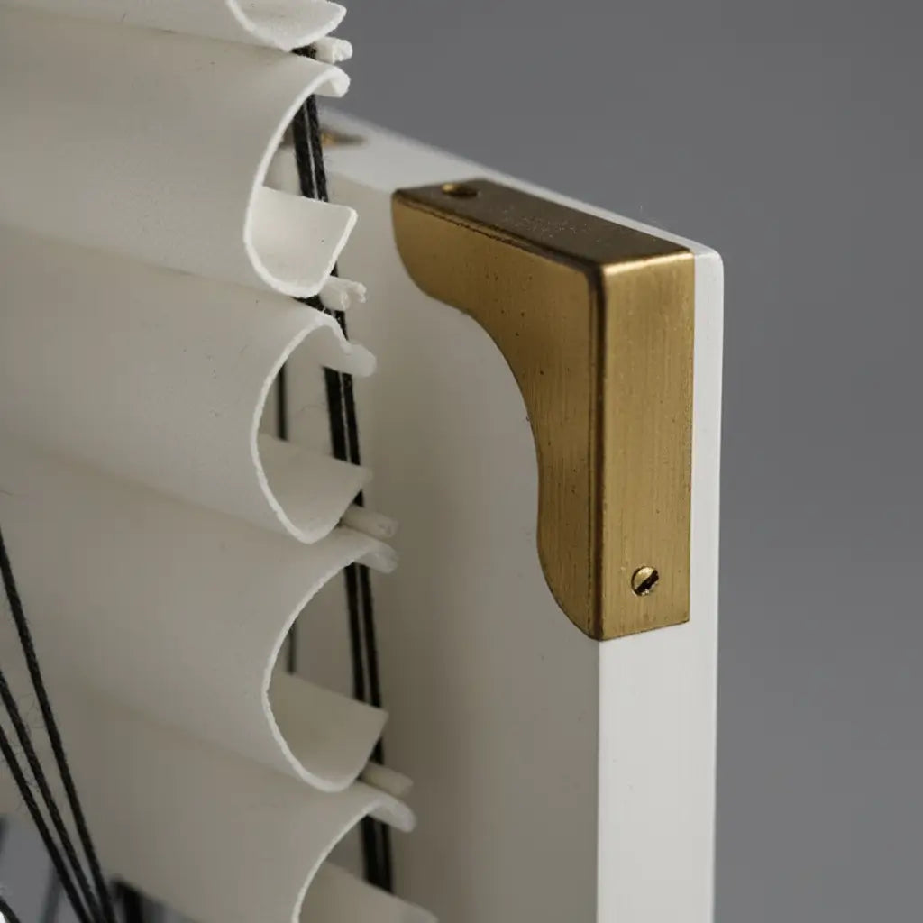 Détail du cale-livre Navire Fantôme blanc montrant la finition dorée du support.