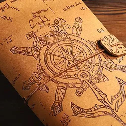 Détail de la couverture d’un journal pirate en cuir avec motif de boussole et cordon de fermeture.
