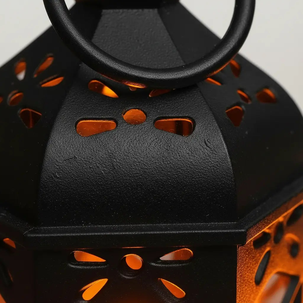 Détail du métal ajouré de la lanterne rétro avec lumière orangée.