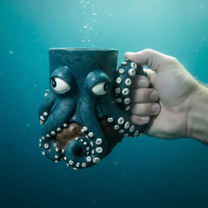 Main tenant le mug Kraken des Profondeurs sous l’eau, ambiance abyssale.