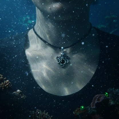Homme portant le pendentif Pieuvre à l’Œil Mystique noir sous l’eau, lumière aquatique diffuse.