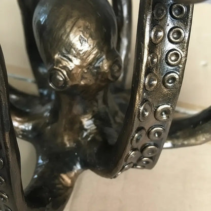 Détail des tentacules sculptées de la pieuvre gardienne des tables en métal patiné.