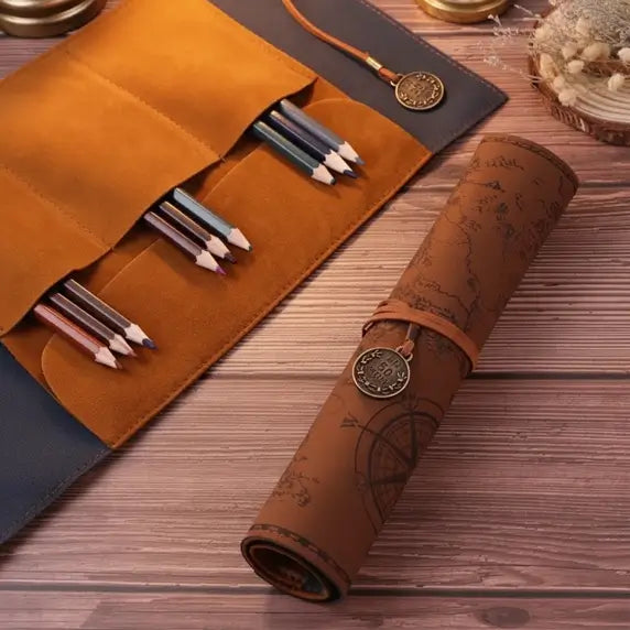 Trousse carte au trésor ouverte contenant des stylos et pinceaux, posée sur table en bois.