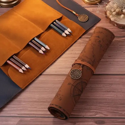 Trousse carte au trésor ouverte contenant des stylos et pinceaux, posée sur table en bois.